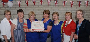 Pictured prior to cutting the Diamond Jubilee cake are ladies who provided lunches for the ‘traditional street party'.  L to R: Roberta Campbell, Sarah Nettleship, Valerie Harron, Yvonne Belshaw, Ruby Hamill, Elizabeth Park, Isobel McAuley and Elizabeth Park.