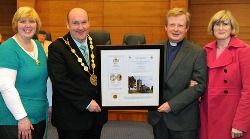 The Mayor of Lisburn, Alderman William Leathem presents a gift to the Rev Nicholas Dark (Mayor's Chaplain) recording events held at Magheragall Parish Church to celebrate the Queen's Diamond Jubilee.  Looking on are the Mayoress, Kathleen Leathem (left) and the rector's wife, Bronwen Dark (right).
