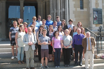 Caius College Choir members with Bishop Alan and guide Mr Paul Gilmore on the steps of St Anne's before their tour of the Cathedral.