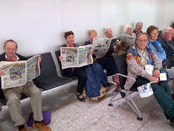 Some of the Connor pilgrims catch up on the news as they wait at Heathrow for their flight to Tel Aviv on November 12. Picture: Stephen Forde.