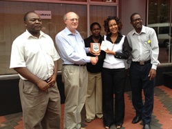 Canon George Irwin presents a Lisburn plaque to staff at the Christian Aid office in Harare.