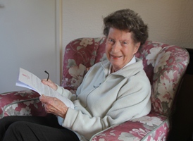 Peggy Weir, MBE, reads a letter giving details of her investiture at Buckingham Palace.