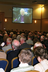 Delegates at the General Synod watch the Archbishop's deliver his presidential address which was relayed on big screens.