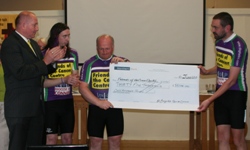 Mr Fordon McKeown, left, Chairman of the Friends of the Cancer Centre, applauds as cyclists Ernie Arthur, Bill Boyce and Andrew Ker present him with a cheque for £35,100.