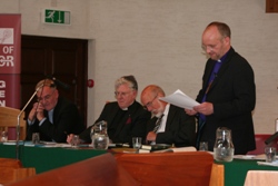 The Bishop of Connor delivers his presidential address. Behind him are the Archdeacon of Belfast, the Ven Barry Dodds, the Dean of Connor, the Very Rev John Bond, and Honorary Lay Secretary Robert Kay.