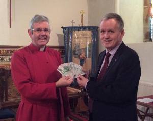 Parish Treasurer, Mr Tommy Lyttle, hands the rector of Larne, Archdeacon Stephen Forde, ₤1,000 in bank notes to give away as he wishes.