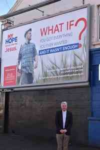 The Ven David McClay at the foot of one of the billboards supporting the showing of the film.