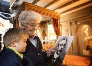 Cairncastle parishioner Eleanor Thompson shows her great grandson a photo of her father Ambrose Willis,  chief interior design draughtsman on the Titanic. Photo: Titanic Belfast.