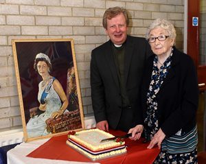 Charlotte Dickson, aged 98, helps the Rev Nicholas Dark cut the cake at the Queen's 90th birthday celebration in Magheragall.