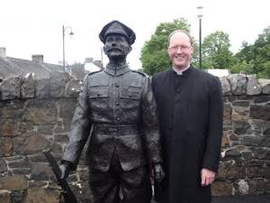 The Rev John Anderson with the statue of Rifleman Robert Quigg VC, which stands in Bushmills.