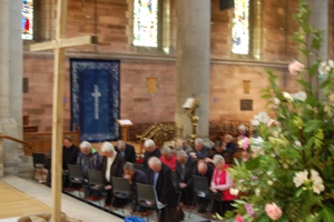Clergy kneel to pray at the foot of the large wooden cross erected in St Anne's Cathedral for the Divine Healing Ministries Day of Prayer for God's Peace.