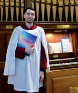 All Saints’, Eglantine, organist Jonathan Houston beside the church’s aged pipe organ.